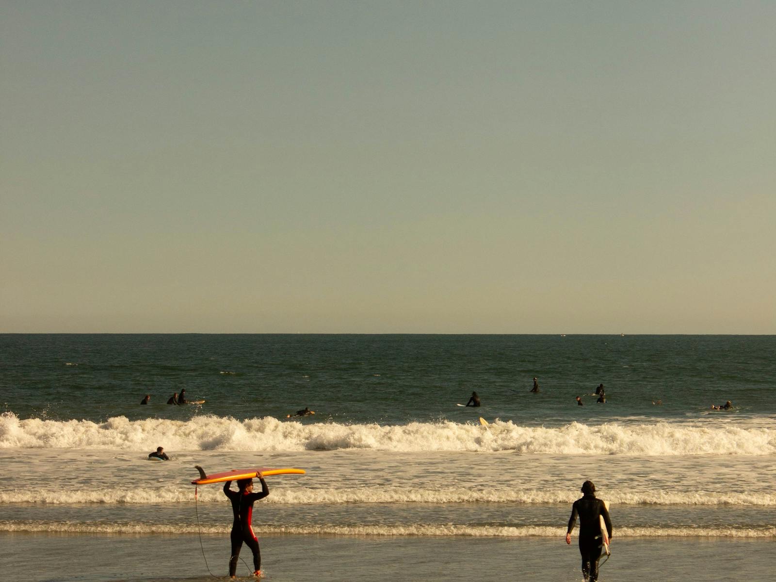Surfers entering the waves at Narragansett Beach near sunset